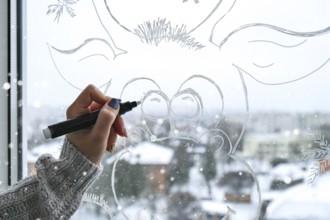 Female hand painting Christmas deer painted on window glass. Christmas winter decor on the window