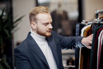 A focused man browses jackets in a clothing store, conveying a sense of style and interest