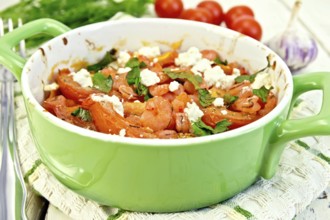 Shrimp and tomatoes baked with feta cheese in a roasting pan on a kitchen towel, parsley and garlic