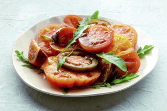 Fresh tomato and rocket salad. A variety of tomatoes of different sorts with arugula leaves.