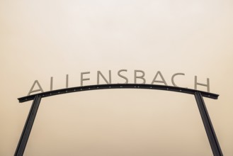 Metal sign with the lettering Allensbach in front of a beige sky with Sahara dust, harbour,