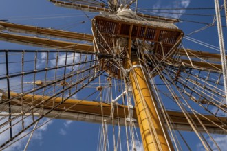 Low angle view of sailboat wooden ship masts and rigging under blue sky with clouds
