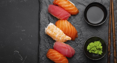 Traditional Japanese sushi with soy sauce, wasabi, chopsticks top view on dark black rustic slate.