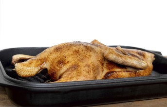 Close-up of a whole roasted or slow-baked duck in a frying pan