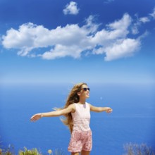 Blond girl shaking hair on air at blue Mediterranean sea tourist in Spain open hands