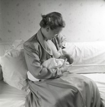 1950s mother nursing her baby. A young woman breastfeeding her baby at home. Sweden 1951 Neg CV/24