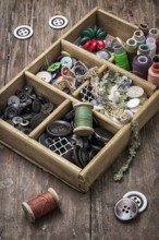 Old wooden box with thread and buttons for needlework in vintage style