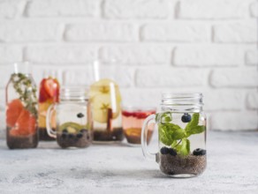 Chia water in mason jar with mint and blueberry on gray cement background. Chia infused detox water