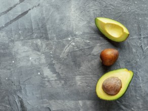 Avocado with copy space. Top view of avocado half, quarter and avocado pit on gray background. Food