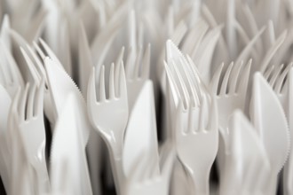 White plastic forks and knifes are seen stacked. Most disposable plastic utensils are made of
