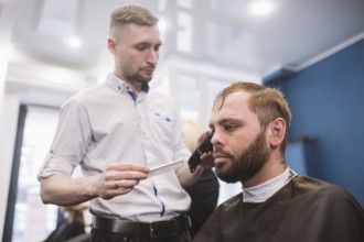Close up shot of a man getting a trendy haircut at a hair salon. Male caucasian hairdresser serving