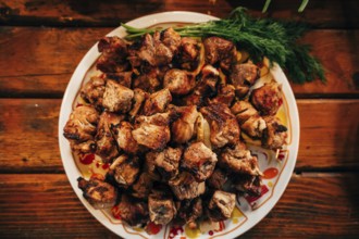 Shish kebab on skewers in a plate on a wooden table