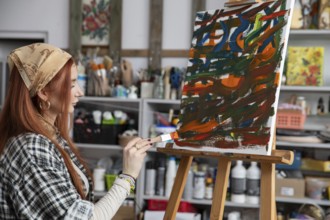 A talented woman artist passionately creates stunning abstract art within her vibrant and colorful