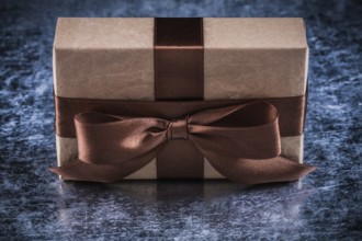 Present box with tied bow on metallic background holiday concept