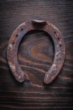 Rusty longstanding horsehoe on vintage dark wooden board construction concept