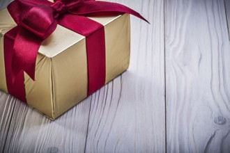 Present box with red knot on wooden board holidays concept