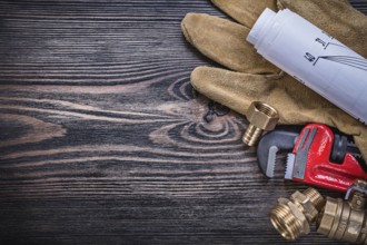 Working gloves pipe wrench engineering drawings brass plumbing fittings on wooden board copy space