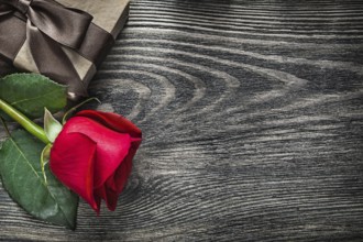 Red rose wrapped present box on wood board copy space holidays concept