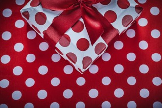 Present box with tied ribbon on polka-dot red tablecloth celebrations concept