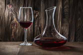 Decanter and glass with red wine on vintage wooden background