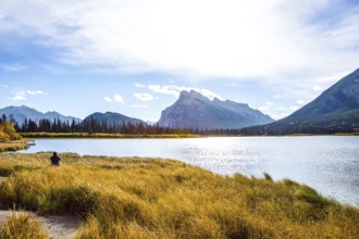Woman photographing a magnificent lake in the Rocky Mountains of Canada. Travel to autumn. Lake