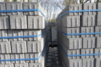 Concrete bricks, secured with blue straps, are being transported on a truck, ready for construction