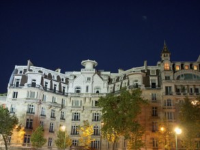 Illuminated building with detailed façade and trees at night, Paris, France, Europe