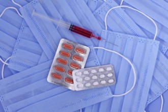 Protective medical mask, pills, syringe on blue background, corona virus protection, Concept of a
