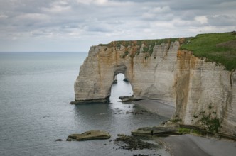 Landscape photo of tall, steep limestone cliffs by the ocean with one with a hole in it creating an
