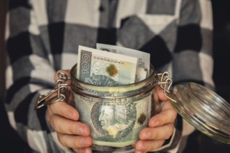 Polish zloty banknote saving money in glass jar. Unrecognizable woman moderate consumption and