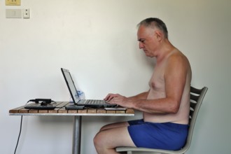 Businessman, freelancer, 60 plus on holiday working with laptop and mobile phone, Pattaya,