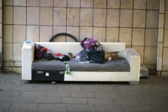 The sleeping place of a homeless person under a bridge with blankets, rubbish and leftover food