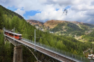 Zermatt, Switzerland. Gornergrat red tourist train on the bridge and Matterhorn peak panorama in