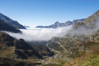 Situation on Susten pass on a sunny autumn day. View into the valley filled with fog with the pass