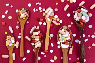 Different colorful pills and capsules in wooden spoons. Global pharmaceutical industry for billions