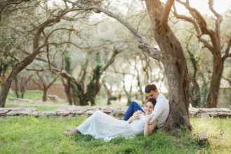 Kotor, Montenegro - 21.06.17: Seated man hugs a woman lying next to him on green grass and kisses