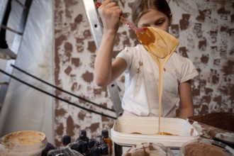 A young girl is happily painting and joyfully showcasing her creativity in a beautiful, rustic