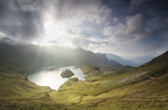 Autumn sunlight through clouds over alpine lake