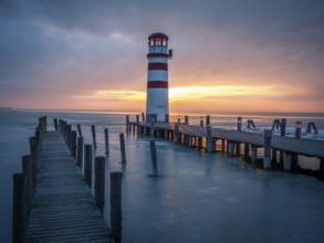 Winter landscape with lighthouse on a lake at sunset