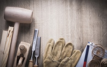 Composition of carpenter??™s tools shavings and leather gloves on wooden board construction concept