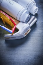 Close up rolled up blueprints hammer goggles