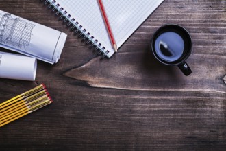Copybook pencil blueprints wooden meter and cup of coffee on pine wood board construction