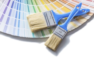 Two brushes with blue handles on color palette isolated on white