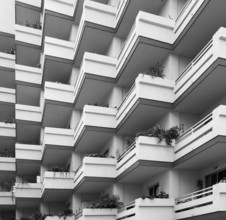 Monochrome image of repeating balconies on large modern concrete apartment building with house