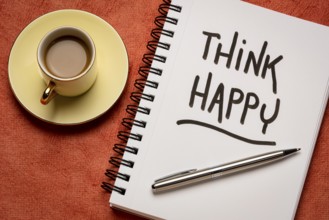 Think happy inspirational handwriting in a sketchbook with a cup of coffee, personal development,