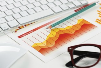 Business workplace with keyboard glasses and financial documents on table