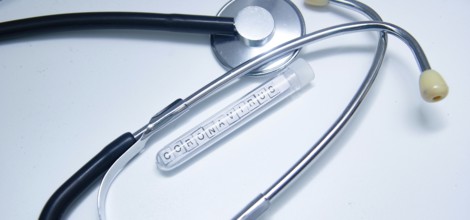 Coronavirus-labeled test tube beside a stethoscope on a white background