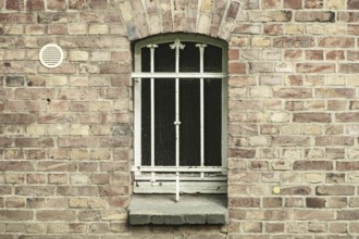 Barred cellar window in a brick wall