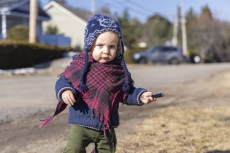 Toddler exploring his local neighborhood on a bright winter day. Portrait of 3 year old child