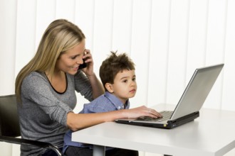 Mother and son at the computer, symbol of working from home, family and career, double burden